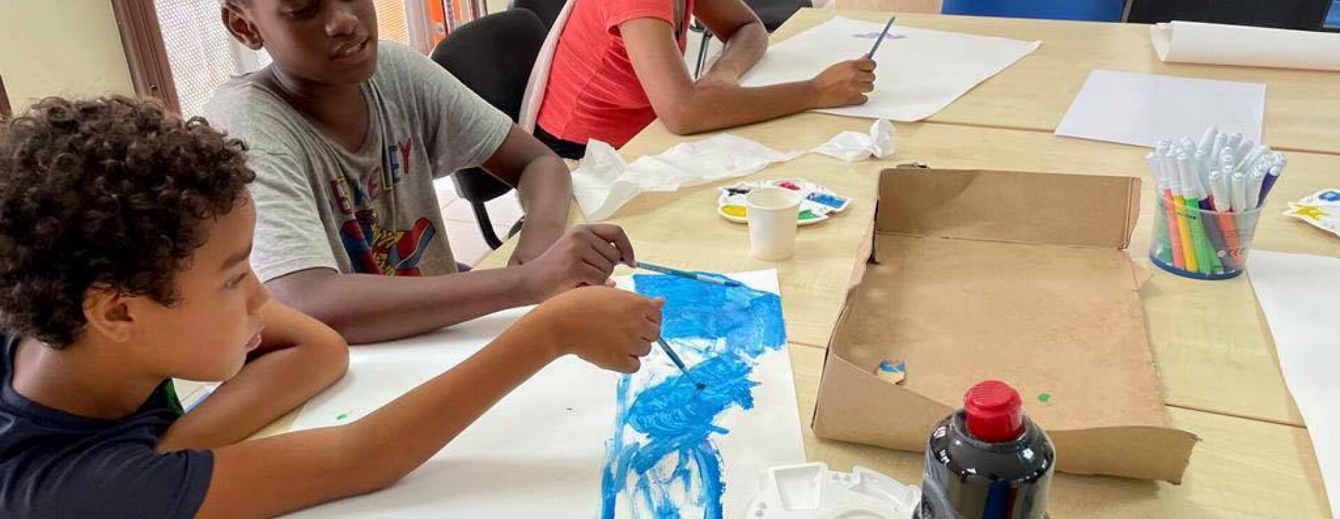 Jeunes enfants peignant sur des feuilles grand format