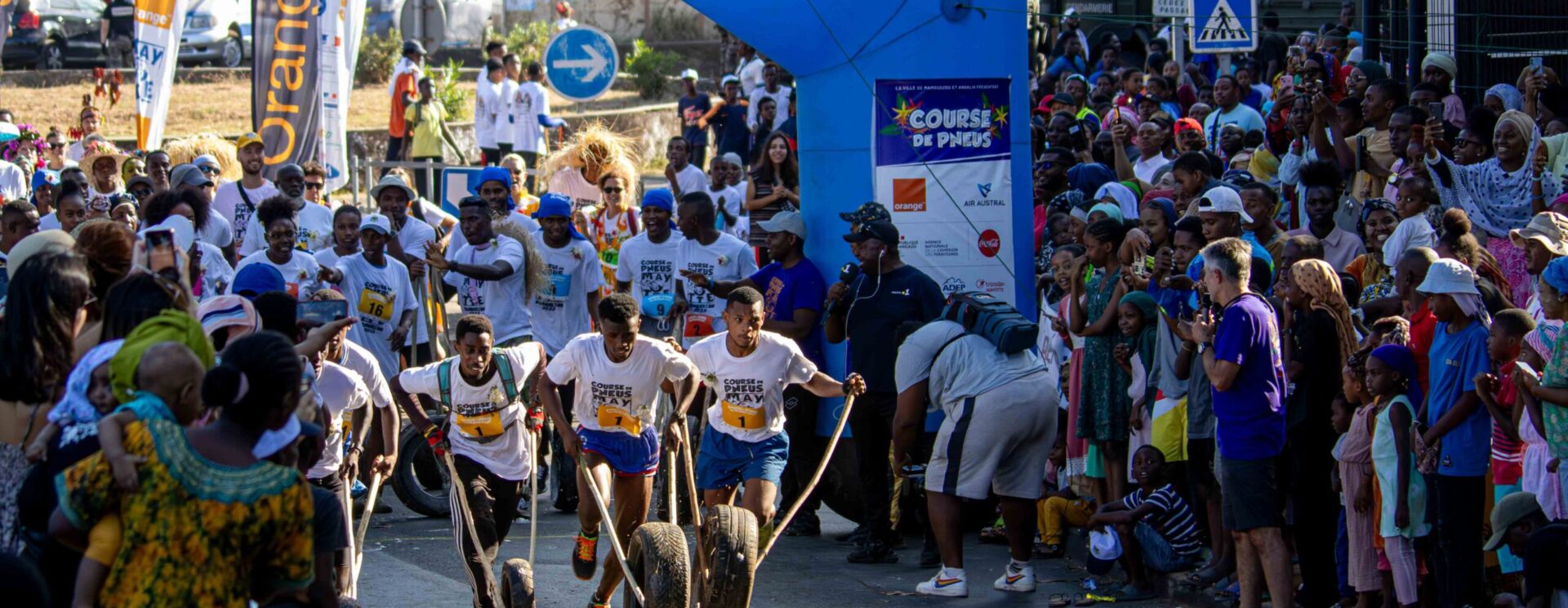 Public encourageant 3 jeunes garçons sur la ligne de départ de la course de pneus