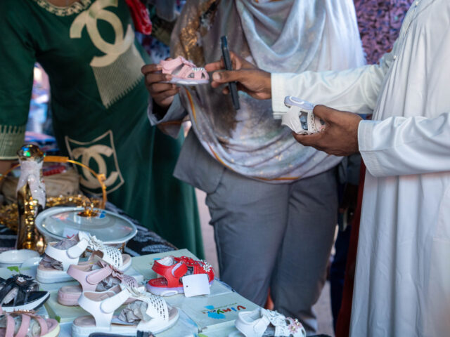 Mains qui tiennent une chaussure d'enfant sur un stand de commerçant de foire à Mamoudzou - Agrandir l'image, fenêtre modale