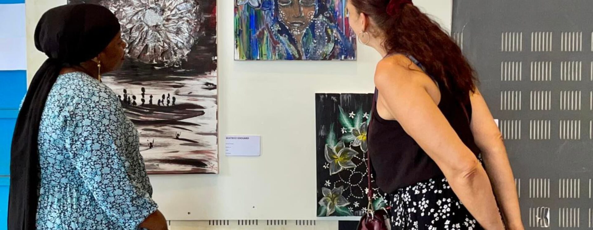 2 femmes observant un tableau de peinture exposé dans une galerie