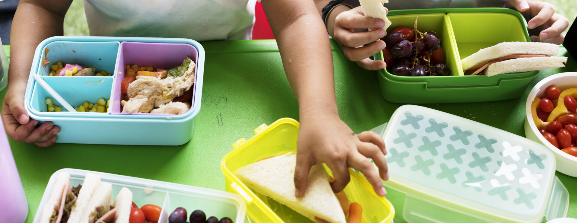Deux enfants assis côte à côte et partageant des boites de déjeuner / goûter