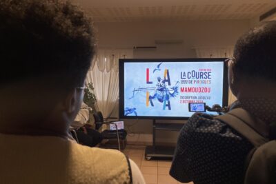 Journalistes de dos regardant la vidéo promotionnelle de la 3ème édition de la course de pirogues de Mamoudzou - Agrandir l'image 4 sur 5, fenêtre modale